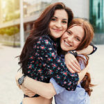 Two cheerful sisters hugging in the park
