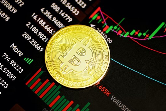 a gold plated bitcoin kept on a screen showing market movements